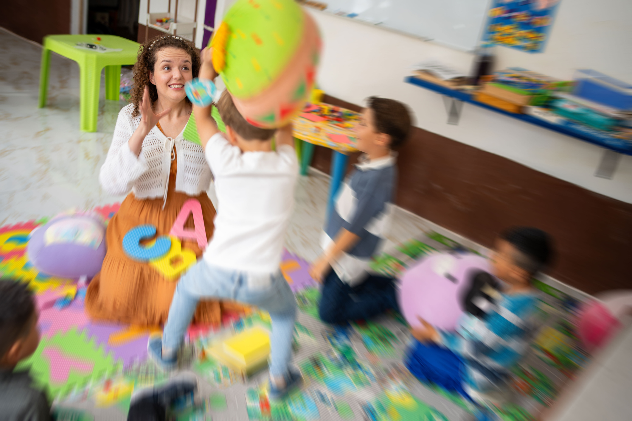 Preschool boy throwing toy at teacher.